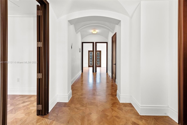 corridor with light parquet flooring, french doors, and vaulted ceiling