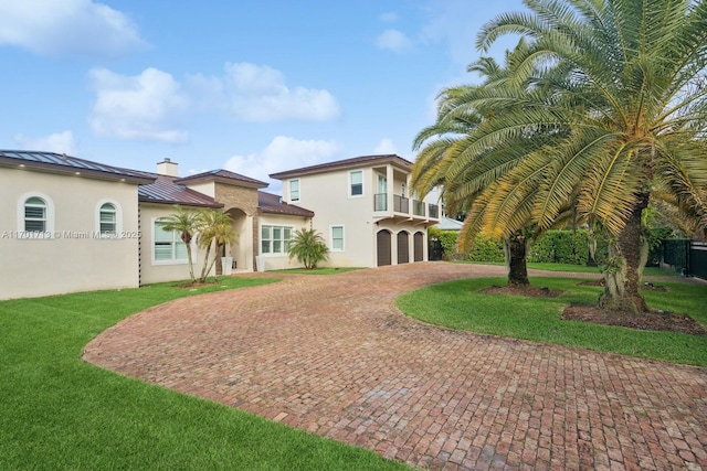 view of front of home with a balcony, a garage, and a front lawn