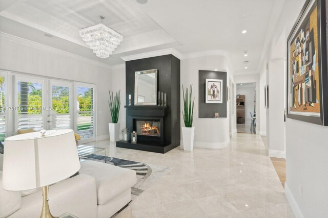 kitchen with wall chimney range hood, a raised ceiling, built in appliances, decorative light fixtures, and a breakfast bar area