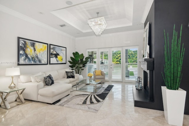 living room featuring a tray ceiling, french doors, a chandelier, and ornamental molding