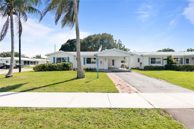 single story home with a carport, aphalt driveway, a front yard, and stucco siding