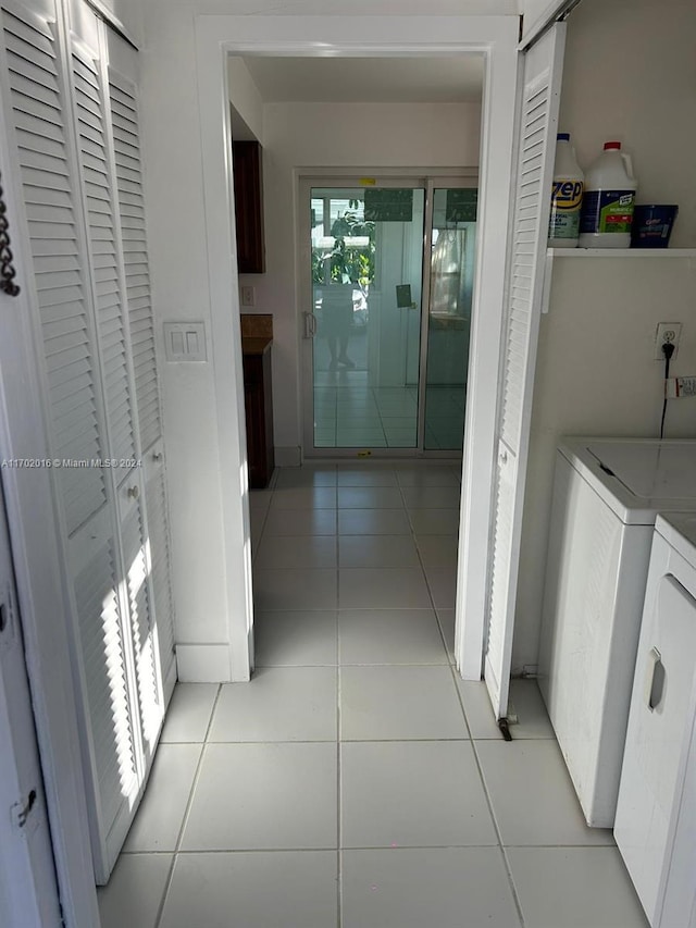 hallway with separate washer and dryer and light tile patterned flooring