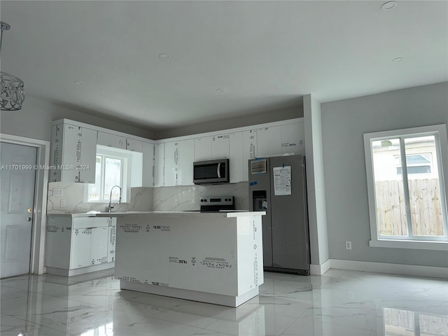 kitchen with sink, a kitchen island, appliances with stainless steel finishes, and white cabinets