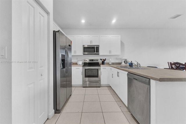 kitchen with white cabinets, appliances with stainless steel finishes, kitchen peninsula, and sink