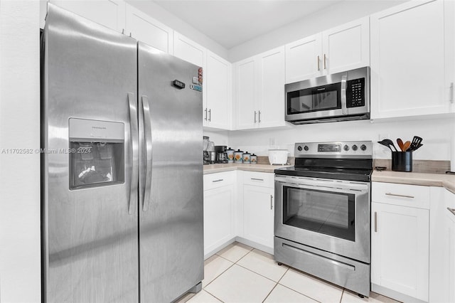 kitchen with white cabinets, light tile patterned floors, and stainless steel appliances