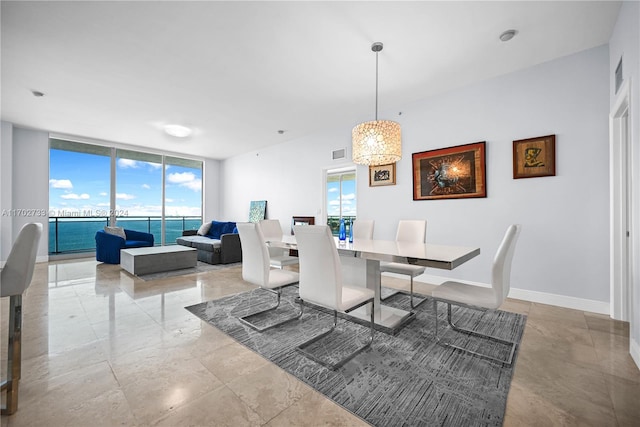 dining room featuring a water view and a wall of windows