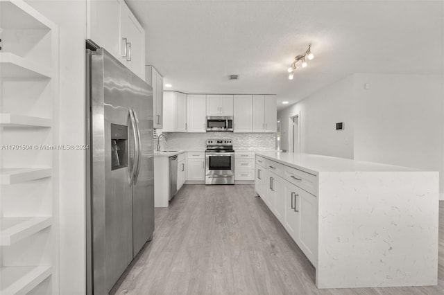 kitchen with white cabinets, sink, light hardwood / wood-style flooring, tasteful backsplash, and stainless steel appliances