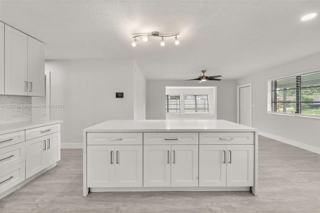 kitchen with backsplash, a textured ceiling, ceiling fan, light hardwood / wood-style flooring, and white cabinets