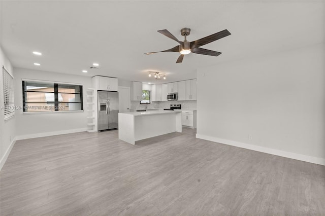 kitchen featuring appliances with stainless steel finishes, light hardwood / wood-style floors, white cabinetry, and a kitchen island