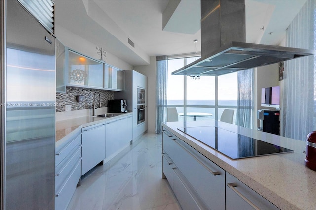 kitchen featuring a water view, sink, built in appliances, white cabinetry, and island exhaust hood