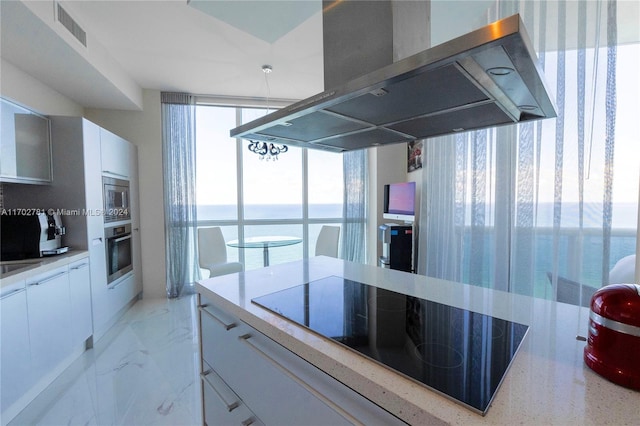 kitchen with island exhaust hood, white cabinets, stainless steel appliances, and floor to ceiling windows