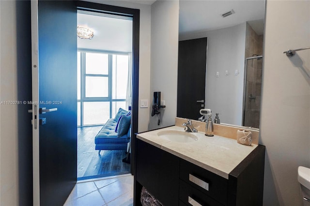 bathroom with toilet, vanity, a shower with shower door, and hardwood / wood-style flooring