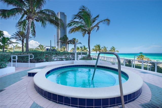 view of swimming pool featuring a water view and a hot tub