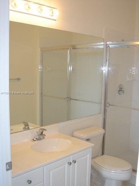 bathroom featuring vanity, toilet, and a shower with shower door