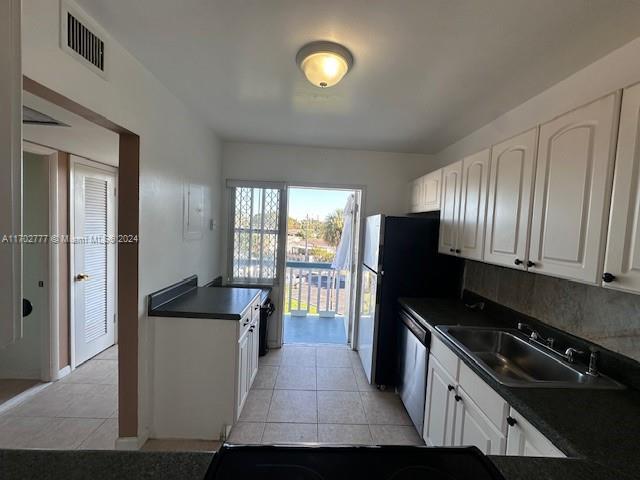 kitchen featuring dishwasher, white cabinets, light tile patterned floors, and sink