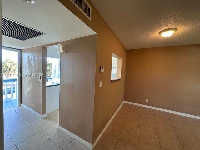 hall featuring light tile patterned floors and a textured ceiling