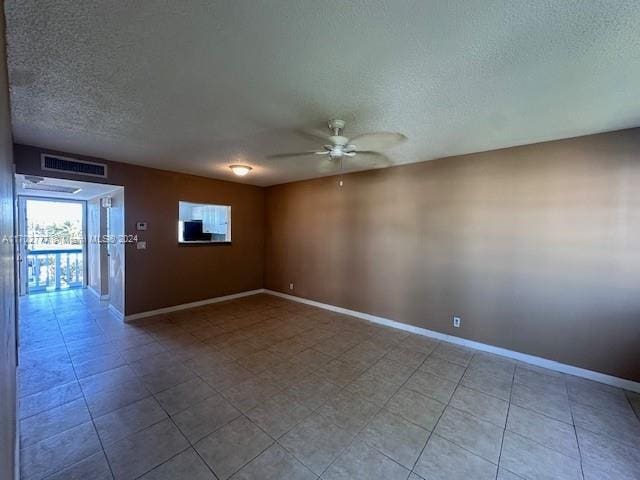 tiled spare room with ceiling fan and a textured ceiling