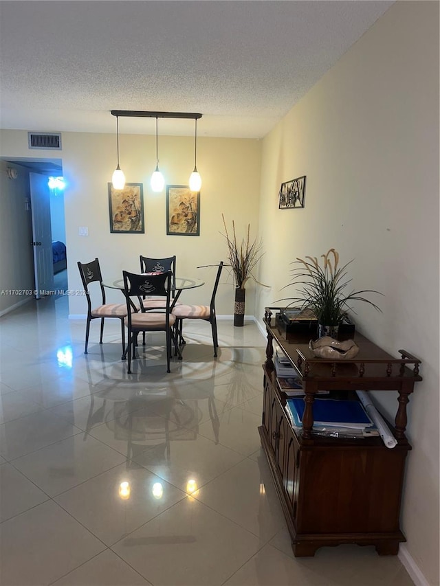 dining area featuring light tile patterned floors and a textured ceiling