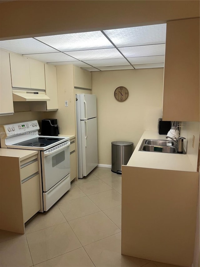 kitchen featuring a paneled ceiling, sink, light tile patterned floors, and white appliances