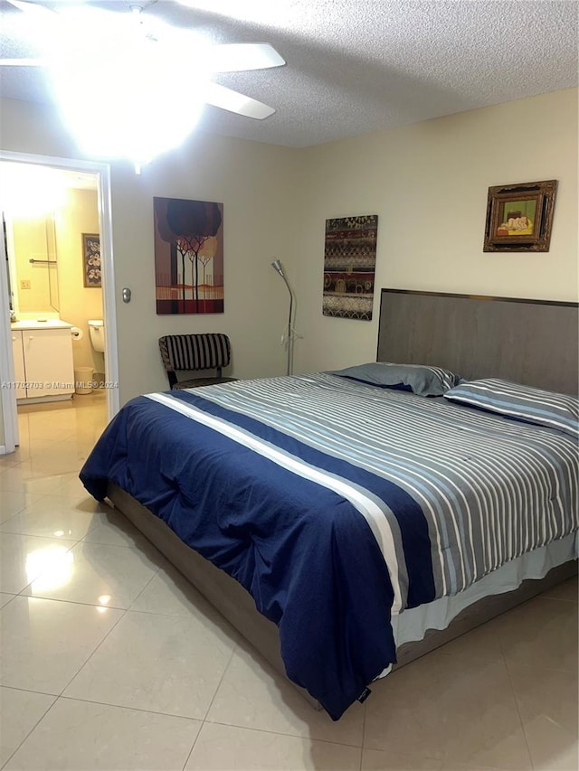 tiled bedroom featuring a textured ceiling, ensuite bath, and ceiling fan