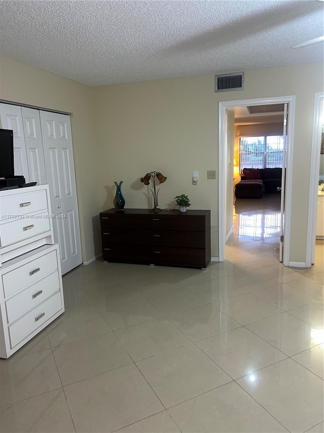 interior space featuring a closet, light tile patterned flooring, and a textured ceiling