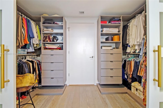 walk in closet with light hardwood / wood-style floors