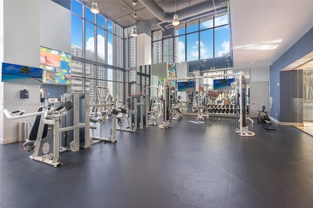 gym featuring ceiling fan, a towering ceiling, and a wealth of natural light