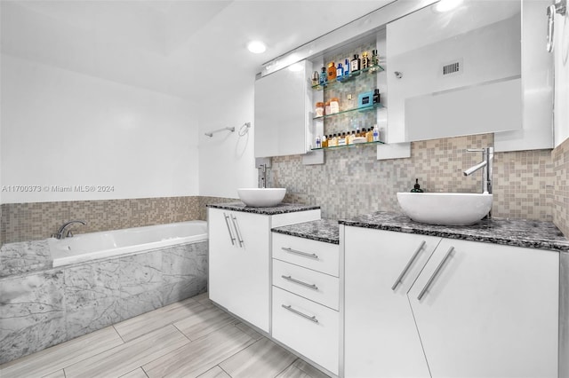 bathroom with vanity and tiled tub