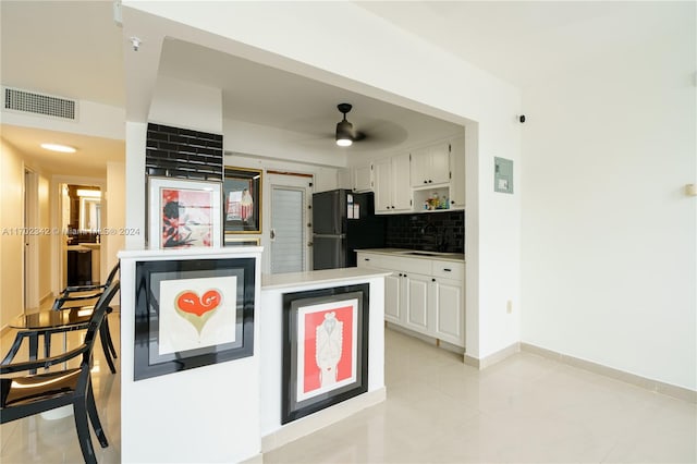 kitchen featuring tasteful backsplash, black fridge, ceiling fan, sink, and white cabinetry