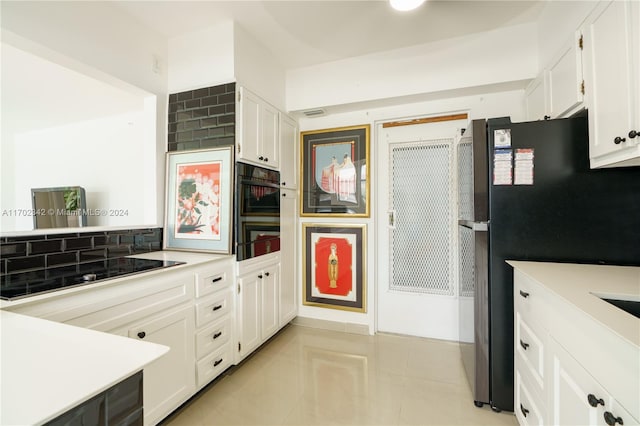 kitchen with stainless steel fridge, decorative backsplash, black electric stovetop, and white cabinets