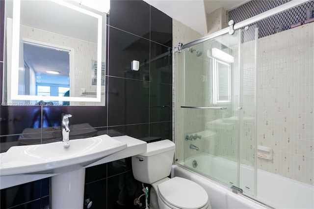 bathroom with toilet, shower / bath combination with glass door, tile walls, and tasteful backsplash