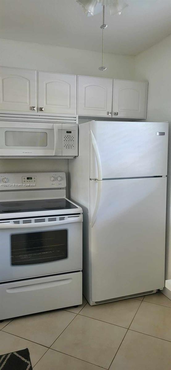 kitchen featuring white cabinets, white appliances, and light tile patterned floors