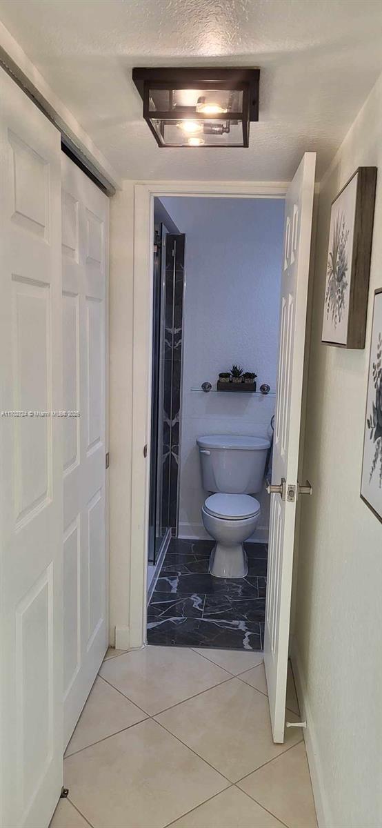 bathroom featuring tile patterned flooring, a textured ceiling, and toilet