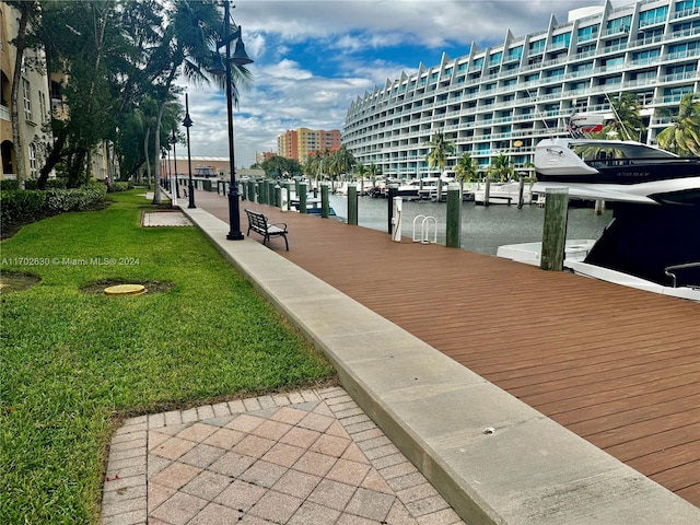 view of community with a boat dock, a water view, and a lawn