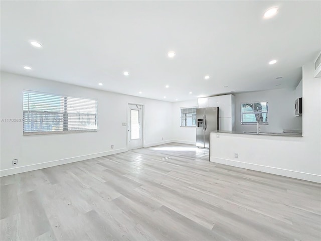 unfurnished living room featuring light hardwood / wood-style floors and sink