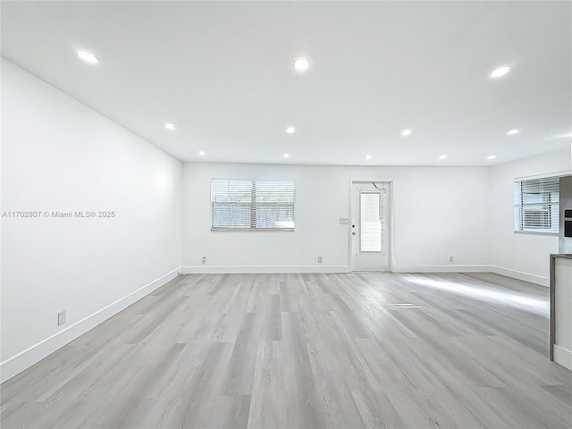 unfurnished living room featuring baseboards, recessed lighting, and light wood finished floors