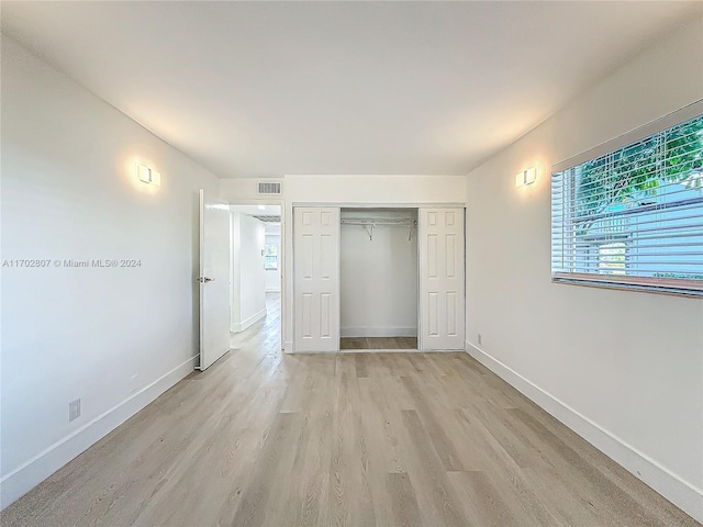 unfurnished bedroom with light hardwood / wood-style flooring and a closet