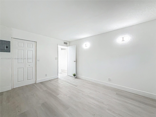 unfurnished bedroom with light wood finished floors, baseboards, and a closet