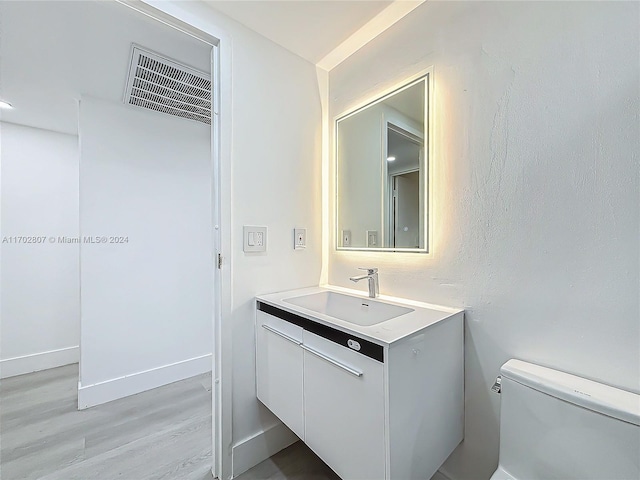 bathroom featuring wood-type flooring, vanity, and toilet