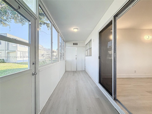corridor with light wood finished floors, healthy amount of natural light, and baseboards