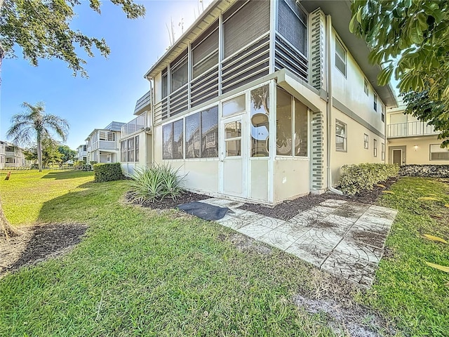 view of home's exterior featuring a yard, stucco siding, and a sunroom