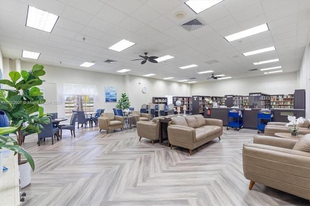 living room with ceiling fan and a drop ceiling