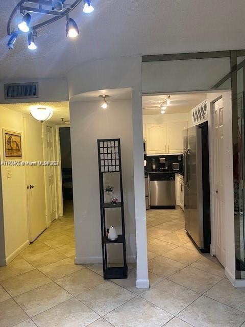 kitchen featuring white cabinets, stainless steel appliances, and light tile patterned floors