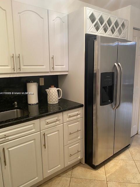 kitchen featuring sink, white cabinetry, stainless steel refrigerator with ice dispenser, and light tile patterned floors