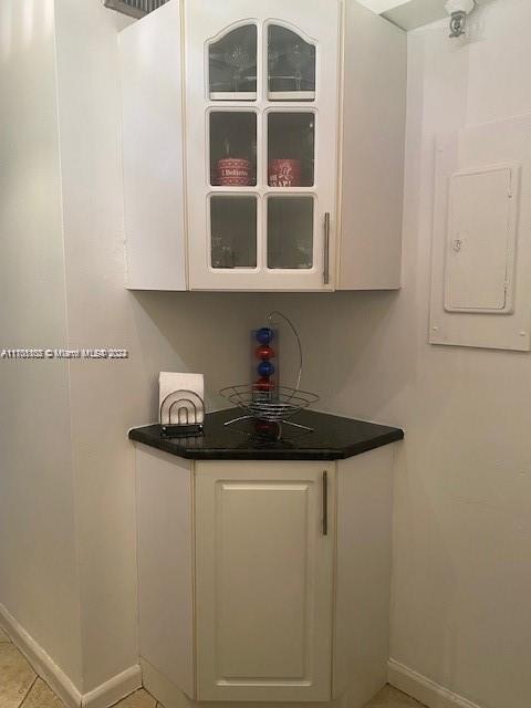 kitchen with white cabinets, light tile patterned flooring, and electric panel