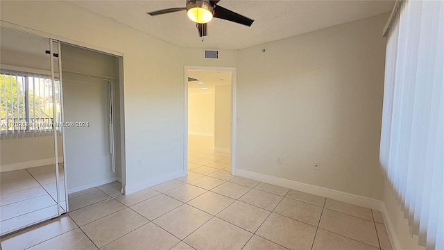 unfurnished bedroom with ceiling fan, a closet, and light tile patterned floors