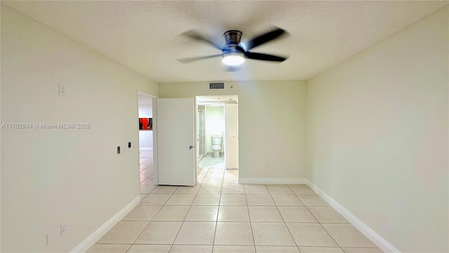 empty room with ceiling fan, a textured ceiling, and light tile patterned floors