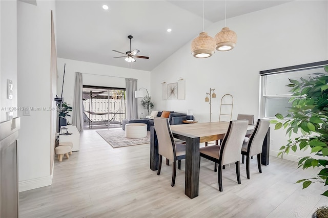 dining space featuring high vaulted ceiling, light wood-type flooring, a ceiling fan, and baseboards