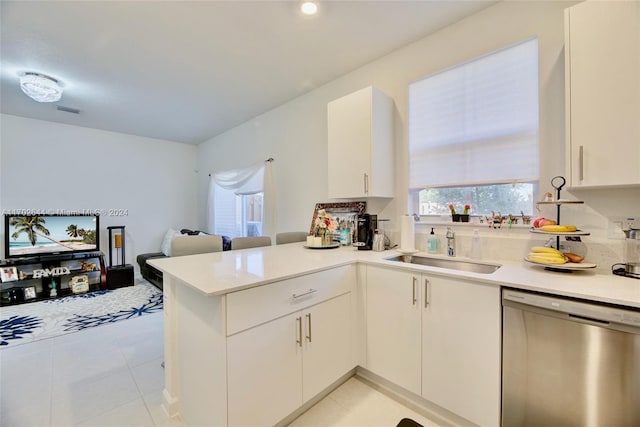 kitchen with dishwasher, kitchen peninsula, white cabinets, and sink