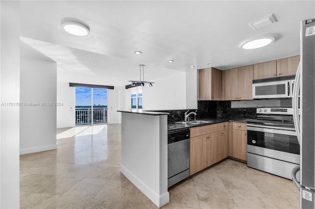 kitchen with kitchen peninsula, appliances with stainless steel finishes, tasteful backsplash, sink, and dark stone countertops